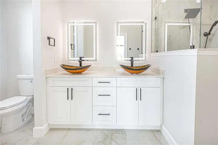 Bathroom with vanity, toilet, and a shower with shower door