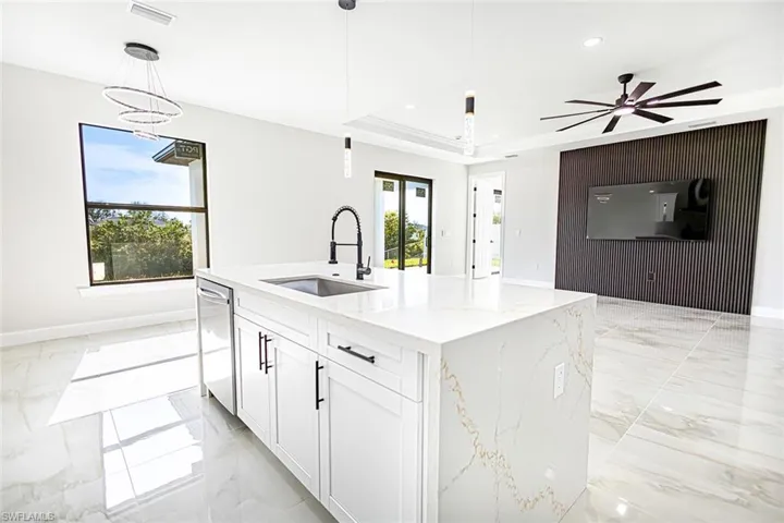 Kitchen featuring pendant lighting, dishwasher, sink, and a kitchen island with sink