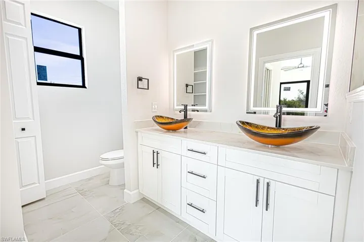 Bathroom featuring ceiling fan, vanity, and toilet