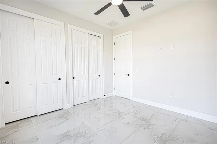 Unfurnished bedroom featuring multiple closets and ceiling fan
