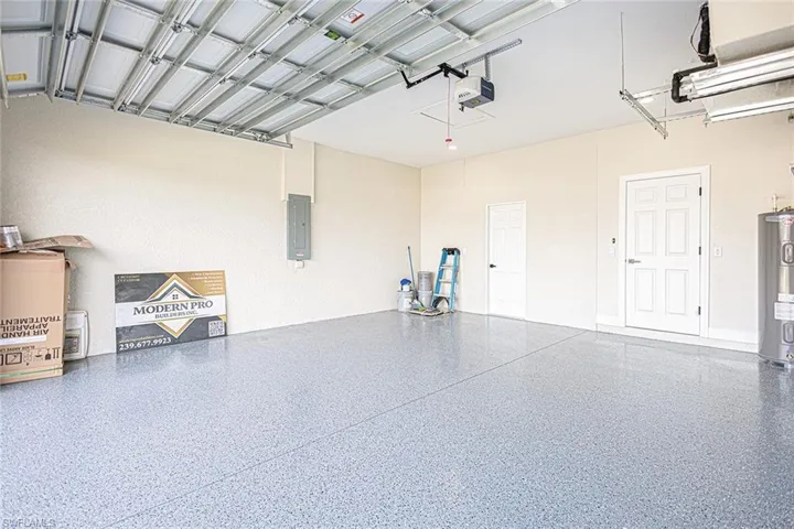 Garage with electric panel, a garage door opener, and water heater