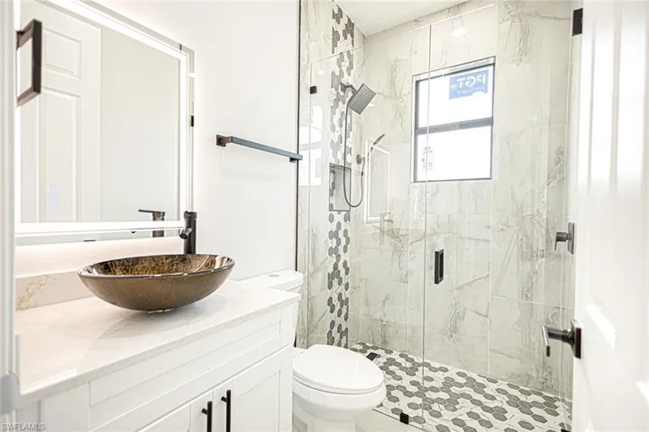 Bathroom with an enclosed shower, vanity, and toilet
