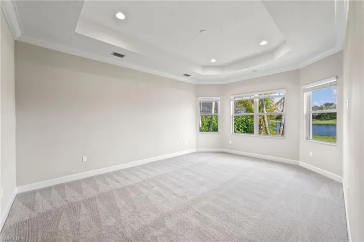 Primary bedroom with crown molding and a tray ceiling