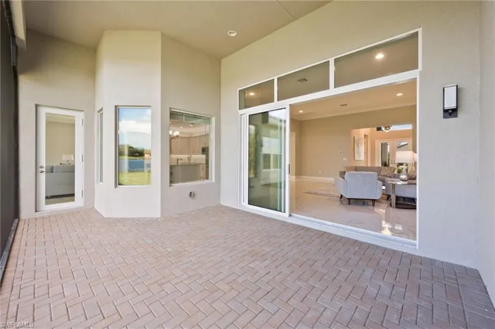 View looking into home from lanai where morning sun floods though stacking sliders, transom windows and glass door make this space flow nicely