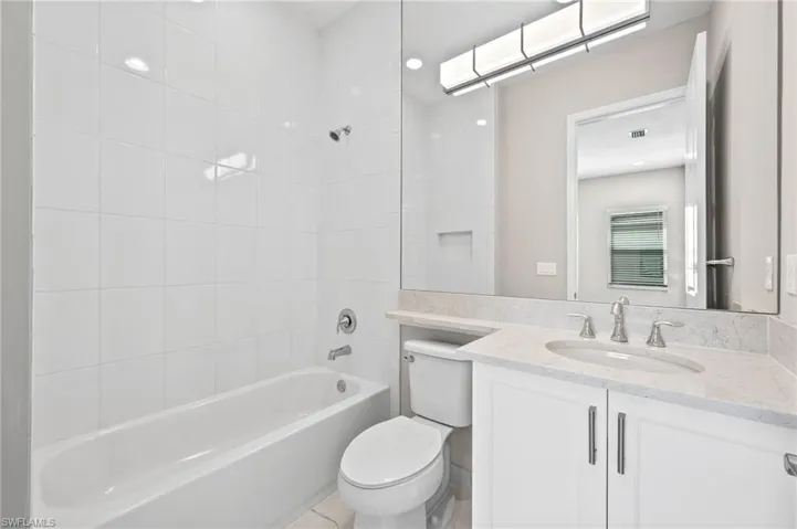 Full bathroom featuring vanity with banjo, and tiled shower / bath combo to the front left of the home