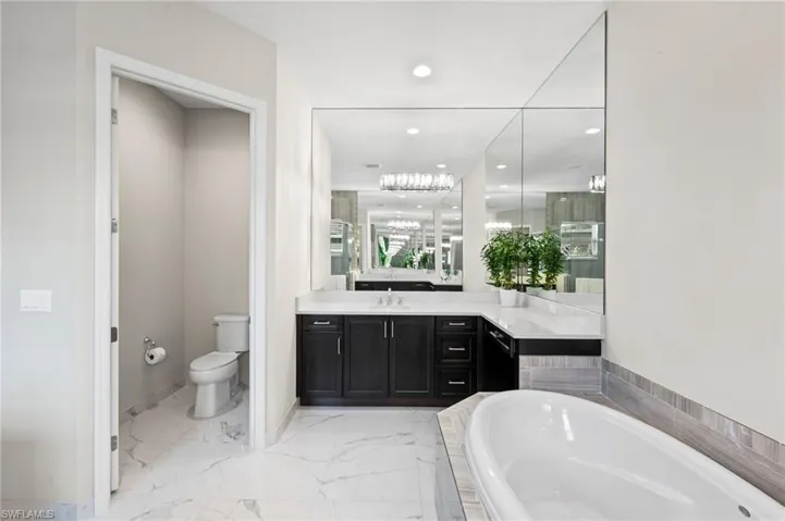 Bathroom with a tub to relax in, vanity, and toilet
