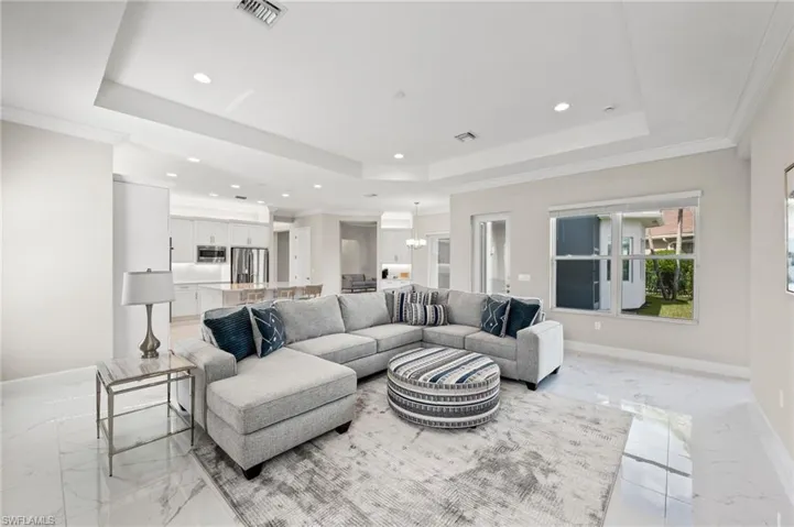 Living room featuring ornamental molding, a notable chandelier, and a raised ceiling