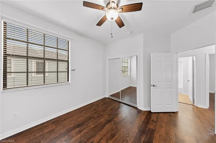 Unfurnished bedroom with dark wood-style flooring, a closet, and ceiling fan