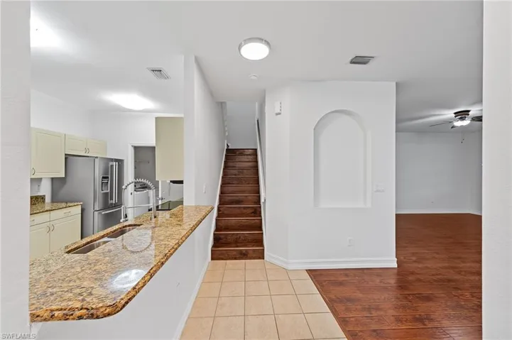 Kitchen with light stone counters, a ceiling fan, light tile patterned flooring, high end fridge, and cream cabinetry