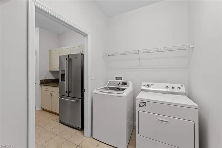 Washroom featuring washing machine and clothes dryer and light tile patterned floors