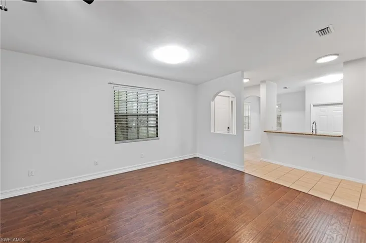 Unfurnished living room featuring dark wood-style floors, arched walkways, and a ceiling fan