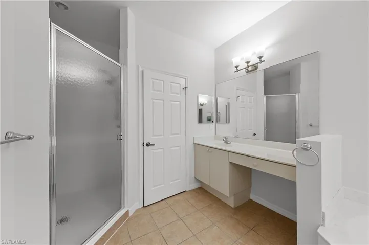 Bathroom featuring a stall shower, vanity, and light tile patterned floors