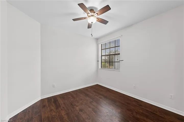 Spare room with dark wood-type flooring and a ceiling fan
