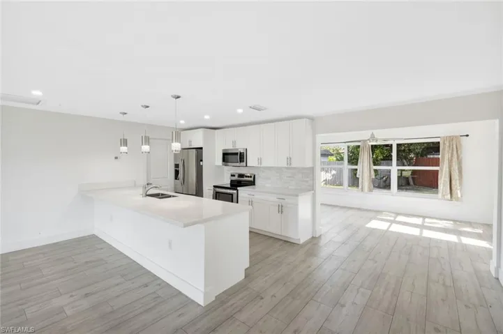 Kitchen featuring decorative backsplash, white cabinets, pendant lighting, a peninsula, and recessed lighting