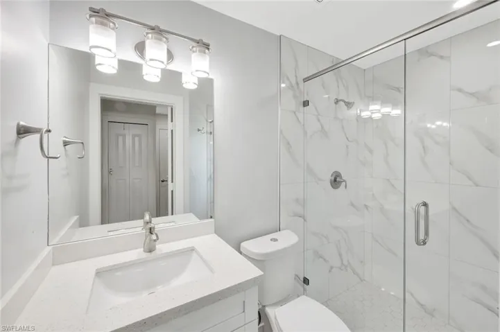 Full bathroom featuring a marble finish shower and vanity