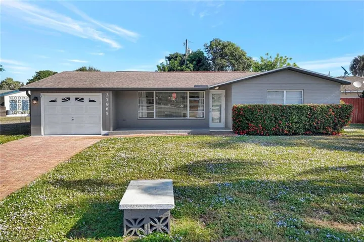 Single story home featuring a front lawn, an attached garage, decorative driveway, and roof with shingles