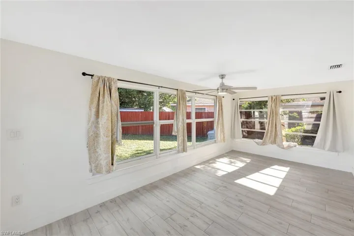 Empty room with plenty of natural light, wood finished floors, and ceiling fan