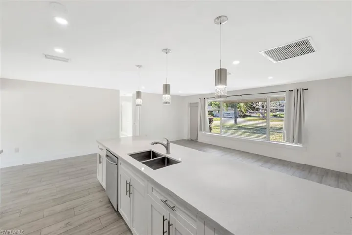 Kitchen with pendant lighting, light wood-type flooring, white cabinets, light stone countertops, and recessed lighting