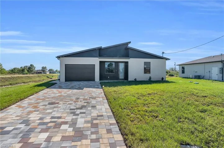 View of front of home featuring central air condition unit, a front lawn, and a garage