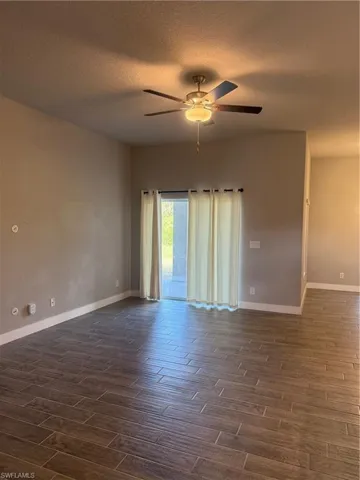 Empty room with dark hardwood / wood-style floors, ceiling fan, and a textured ceiling