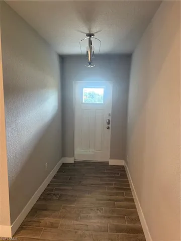 Doorway featuring a textured ceiling and dark wood-type flooring