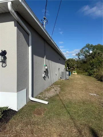 View of side of home with a yard and central air condition unit