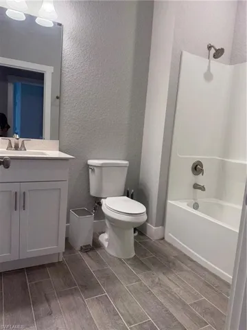 Full bathroom featuring toilet, vanity, tub / shower combination, and hardwood / wood-style flooring