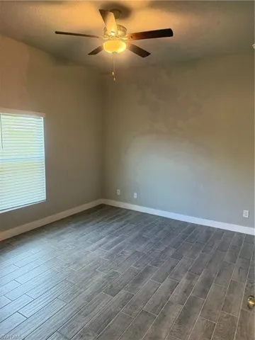 Empty room featuring dark hardwood / wood-style floors, ceiling fan, and a textured ceiling