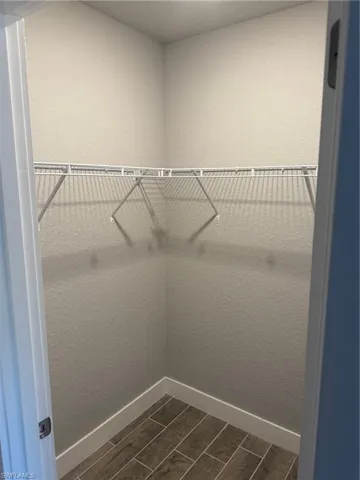 Walk in closet with dark hardwood / wood-style floors