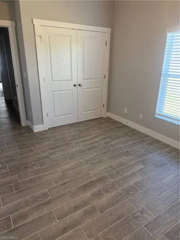 Unfurnished bedroom featuring dark wood-type flooring and a closet