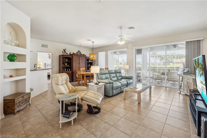 Living room with built in shelves, ceiling fan, a wealth of natural light, and light tile patterned floors