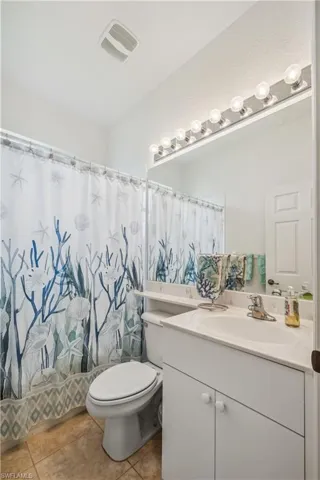 Bathroom featuring vanity, toilet, walk in shower, and tile patterned flooring