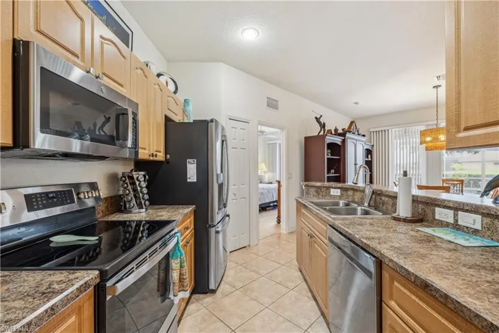 Kitchen with light tile patterned flooring, decorative light fixtures, stainless steel appliances, and sink