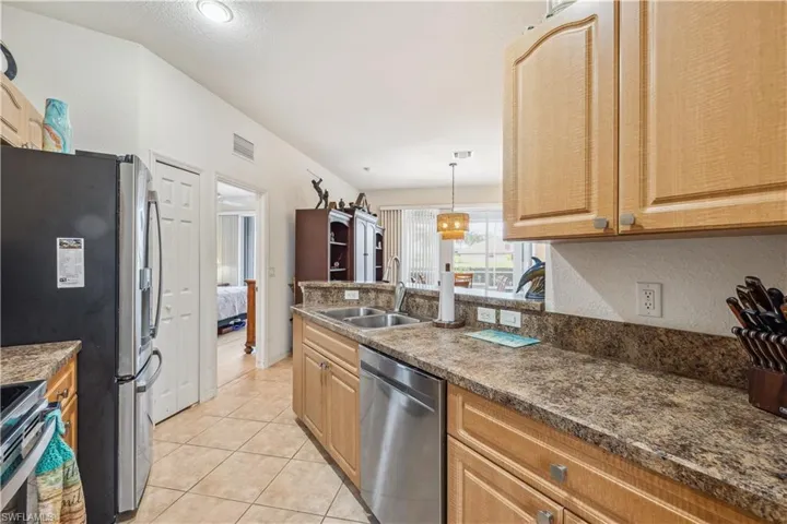 Kitchen featuring stainless steel appliances, sink, decorative light fixtures, and light tile patterned flooring