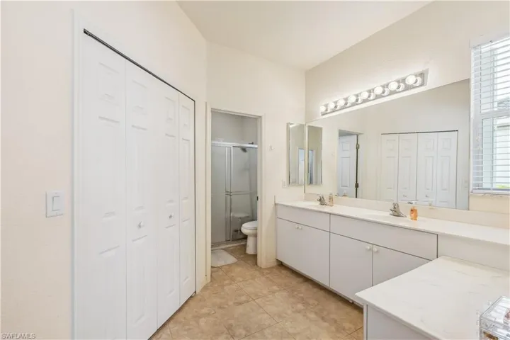 Bathroom featuring vanity, toilet, an enclosed shower, and tile patterned floors
