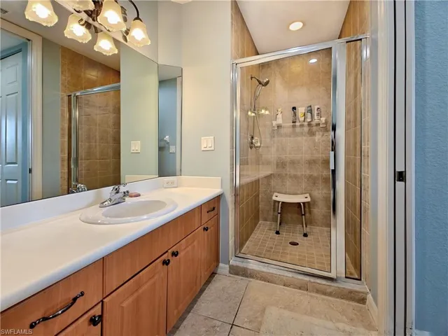 Bathroom featuring vanity, a shower stall, a chandelier, and recessed lighting