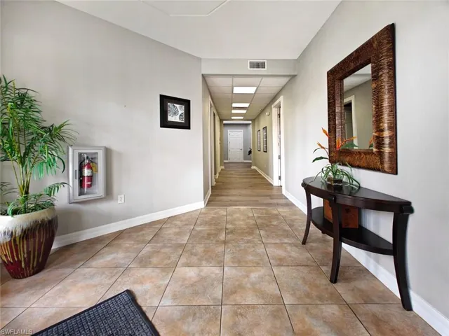 Hall featuring a paneled ceiling and light tile patterned flooring