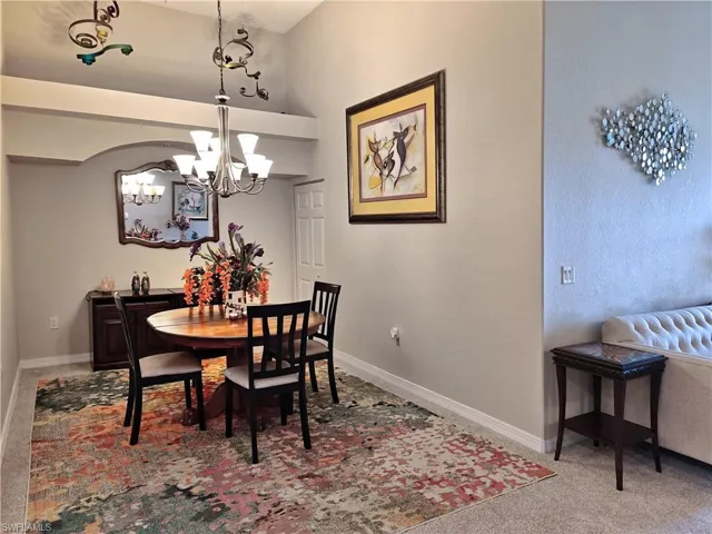 Carpeted dining room with baseboards and a chandelier