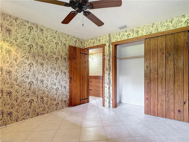 Parlor room featuring beam ceiling, ceiling fan, wooden ceiling, wood walls, and light tile patterned floors