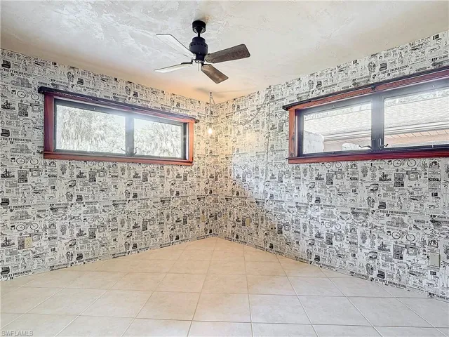 Unfurnished Guest bedroom 1 with ceiling fan, a closet, light tile patterned floors, and wood walls