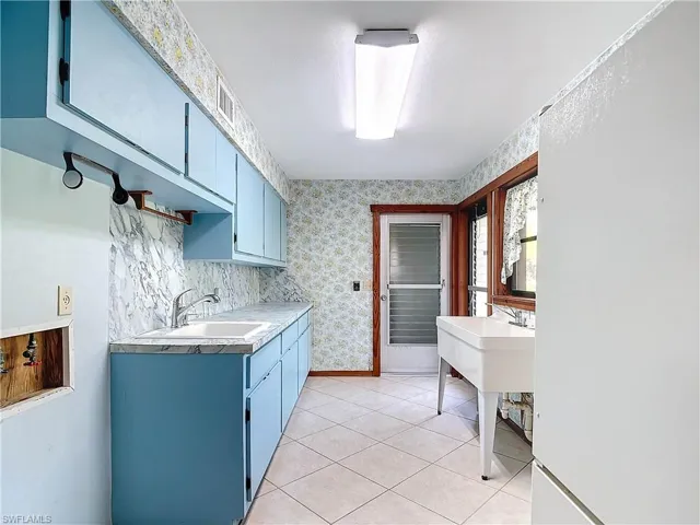 Kitchen with sink, wooden ceiling, custom range hood, and light tile patterned floors