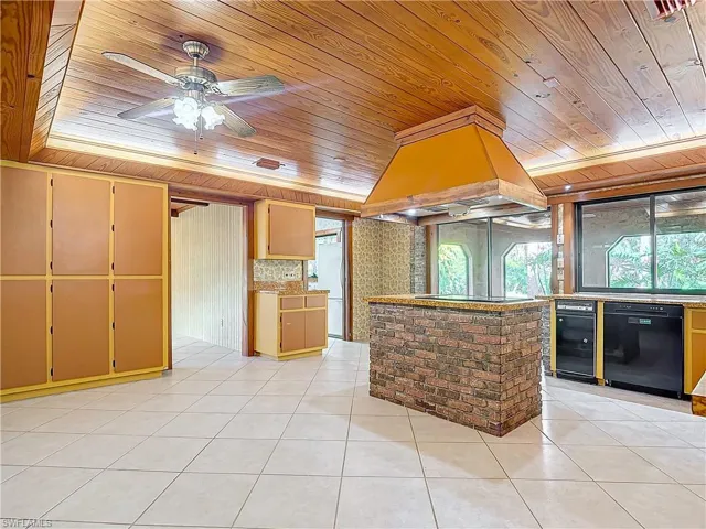 Kitchen featuring custom exhaust hood, plenty of natural light, light tile patterned floors, and wooden ceiling