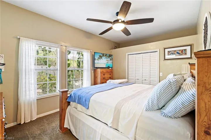 Bedroom with dark carpet, a closet, and ceiling fan