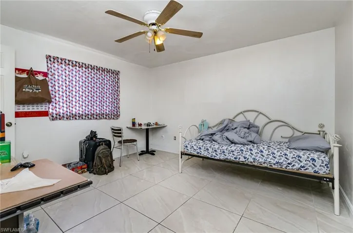 Tiled bedroom featuring ceiling fan