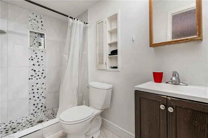 Bathroom with a stall shower, baseboards, vanity, and toilet