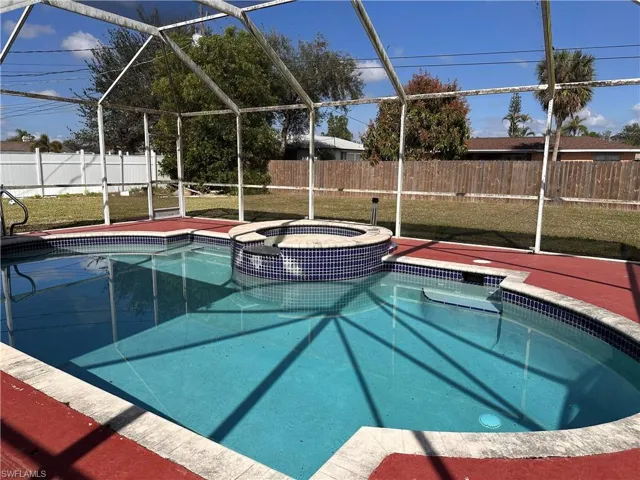 View of swimming pool featuring a yard, an in ground hot tub, and glass enclosure