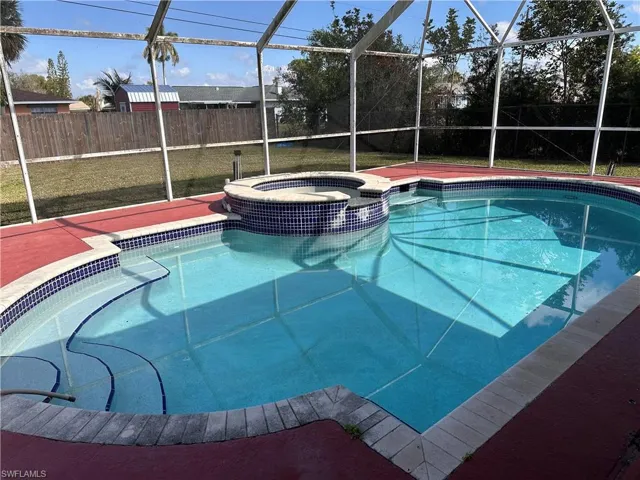 View of pool with glass enclosure and an in ground hot tub