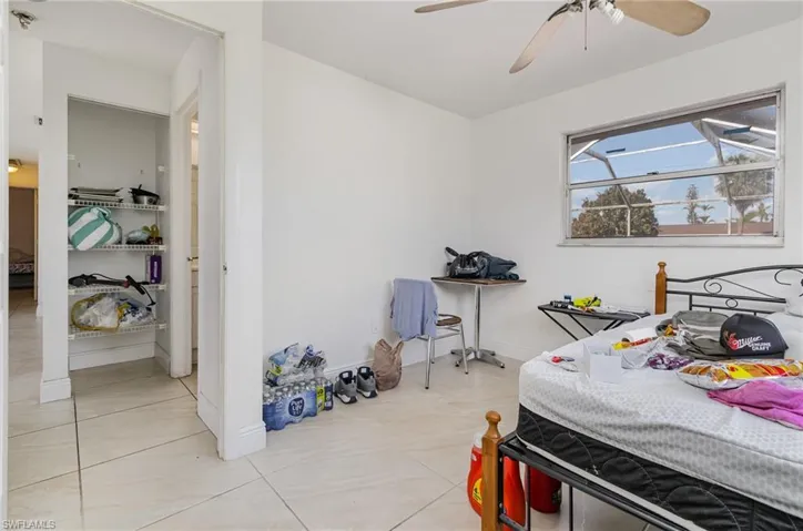 Bedroom featuring a ceiling fan, baseboards, and light tile patterned floors