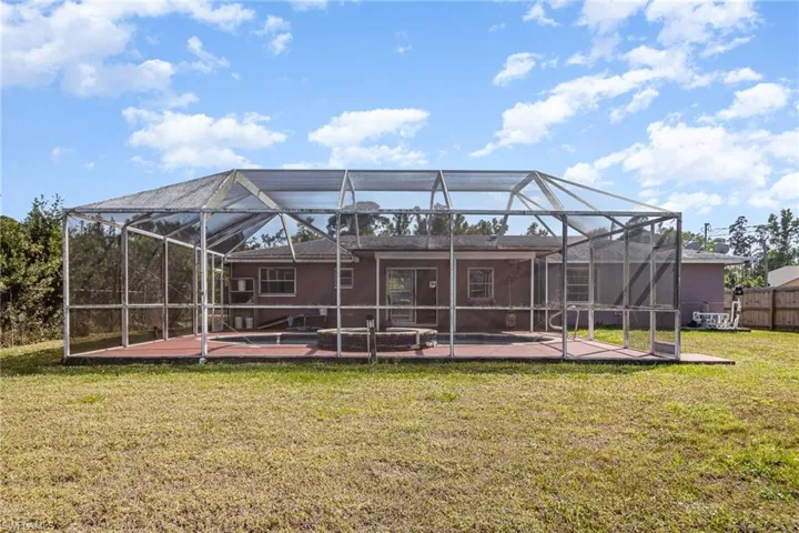Back of house featuring a yard, a lanai, a patio, and fence