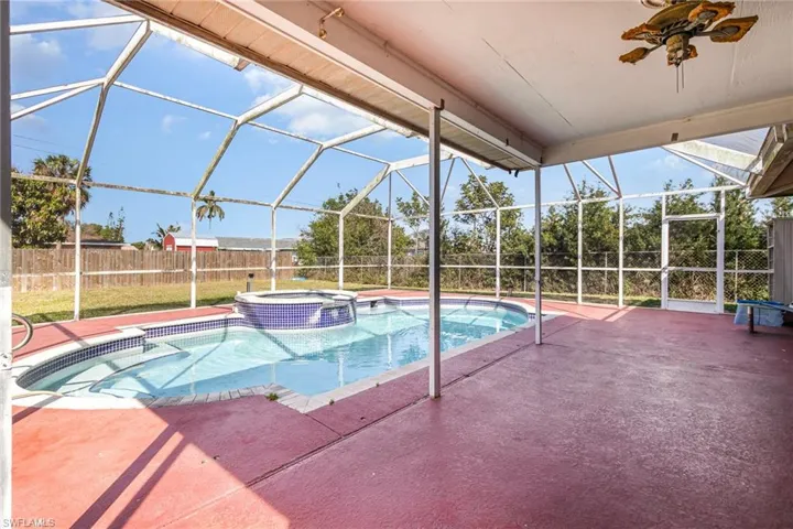 View of pool featuring a pool with connected hot tub, glass enclosure, a patio, and fence